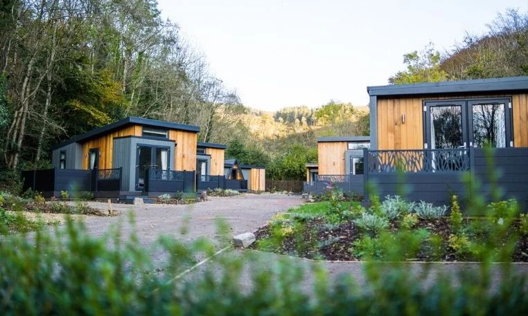 Timber-clad leisure accommodation with private decking in a landscaped woodland setting